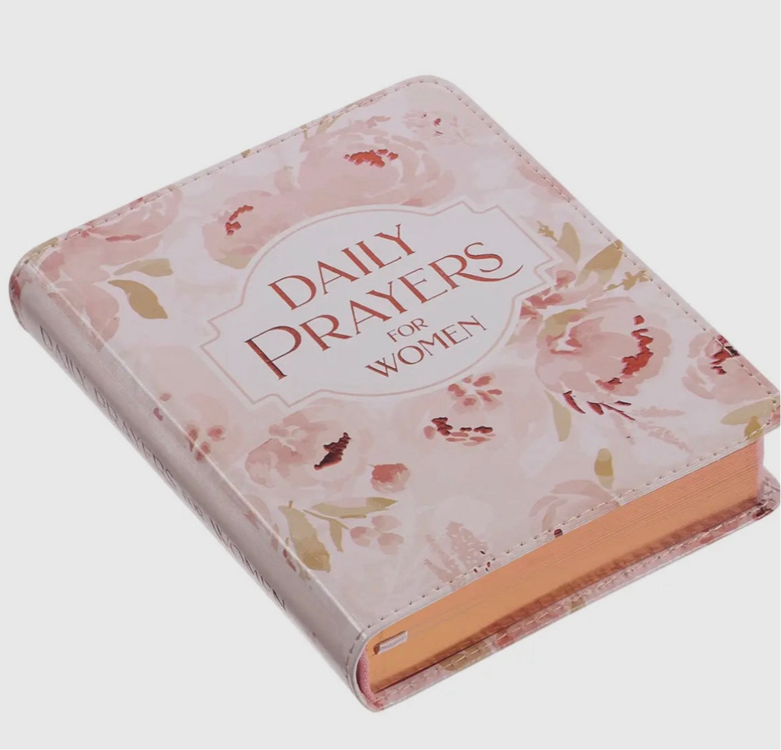 Pink floral hardcover book titled Daily Prayers for Women with gold-edged pages